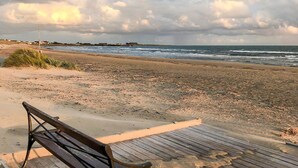 A beach with a wooden bench and a wooden walkway.