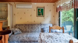 A cozy room with a patterned sofa, a wooden table, and a window with a view of greenery.
