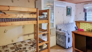 A bunk bed with a wooden frame, a patterned sofa, a small table, and a cabinet.