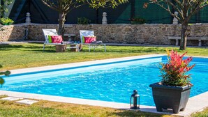 A swimming pool with lounge chairs and a potted plant. - LUXURY SINGULAR VILLA ROSA (PADRON)