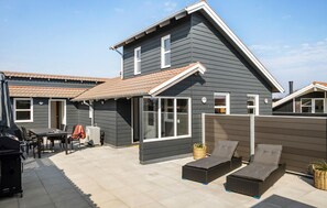 A modern two-story house with a patio area featuring outdoor furniture and a grill. - 2 bedroom cozy home in Otterup (Otterup)