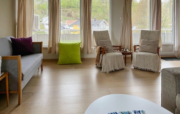 Un salon comprenant un canapé, deux fauteuils, une table basse et un pouf vert vif.