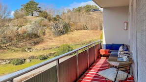 Un balcon doté d’un sol à rayures rouges, d’une table en bois et d’un canapé.