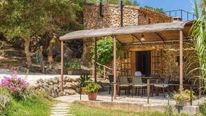 A stone building with a covered patio area featuring outdoor seating.