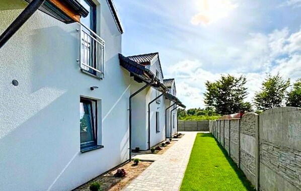 A row of white houses with a narrow pathway and a green lawn.