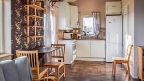 A compact kitchen with wooden cabinets, a microwave, a refrigerator, and a dining area with a table and chairs. - Awesome home in Eslöv with house a panoramic view (Eslöv)