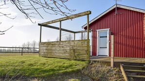 A red building with a white door, a wooden fence, and a grassy area in front. - Awesome home in Eslöv with house a panoramic view (Eslöv)