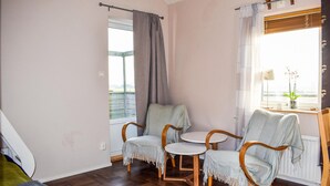 A room with two wooden chairs and a small table, a window with curtains, and a view of the outside. - Awesome home in Eslöv with house a panoramic view (Eslöv)