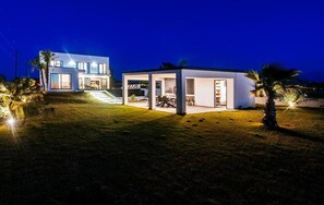 A modern house with a covered outdoor area, a well-maintained lawn, and a clear sky.