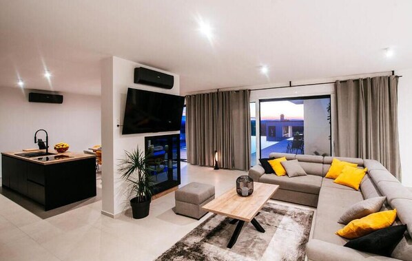 A modern living room with a sofa, coffee table, and a TV mounted on the wall.