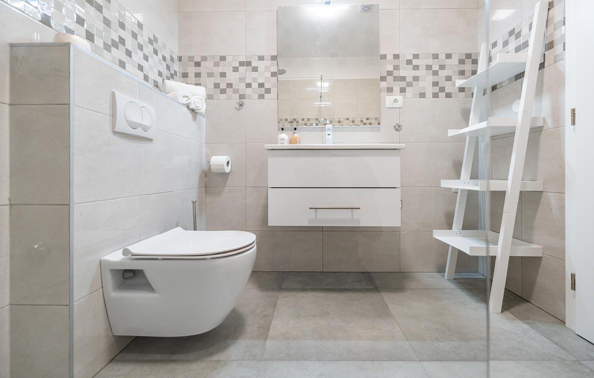 Ein modernes Badezimmer mit Toilette, Waschbecken und Duschbereich.