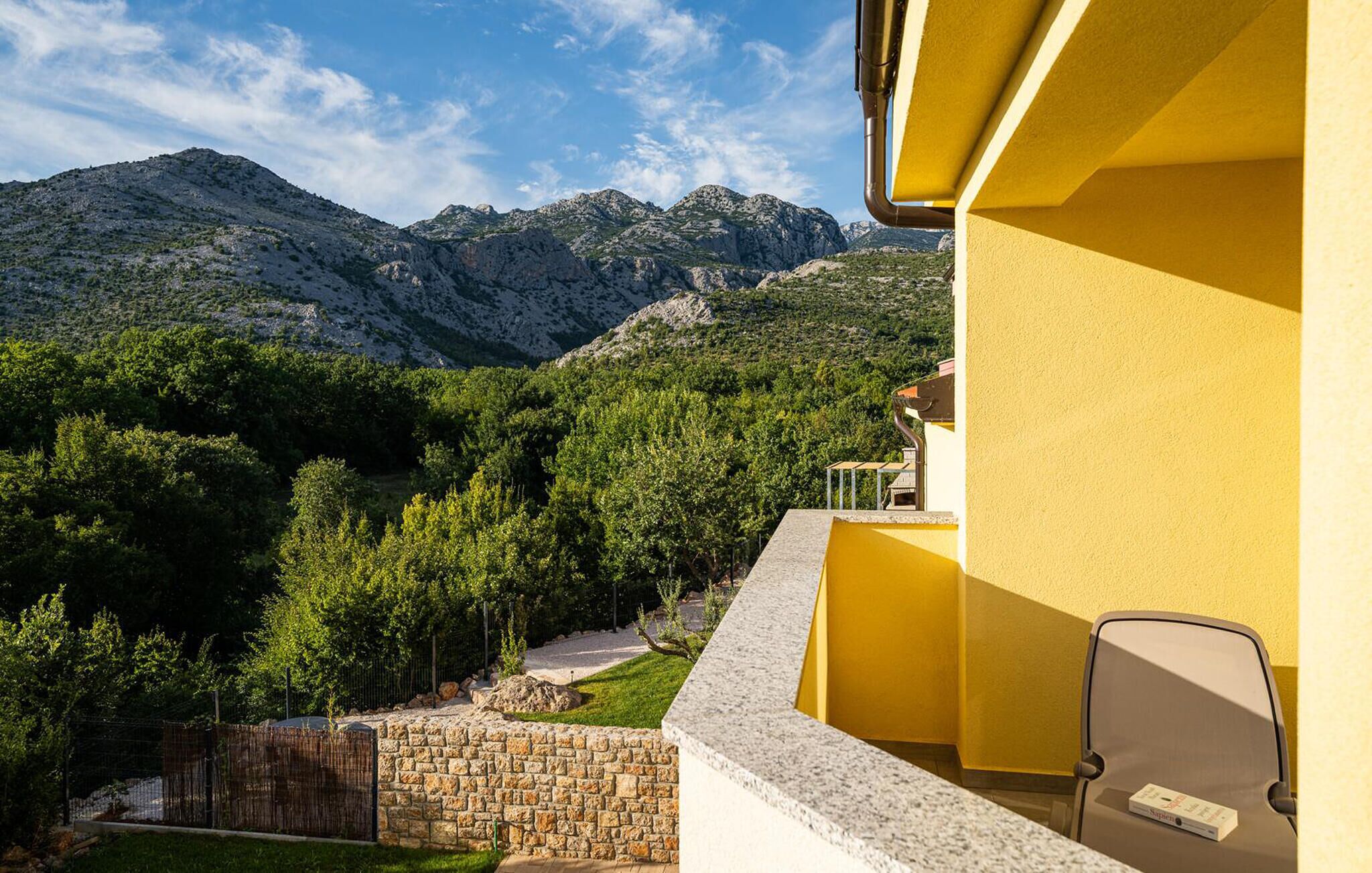 Une chambre d’hôtel avec vue sur les montagnes, un mur en pierre et une façade jaune.