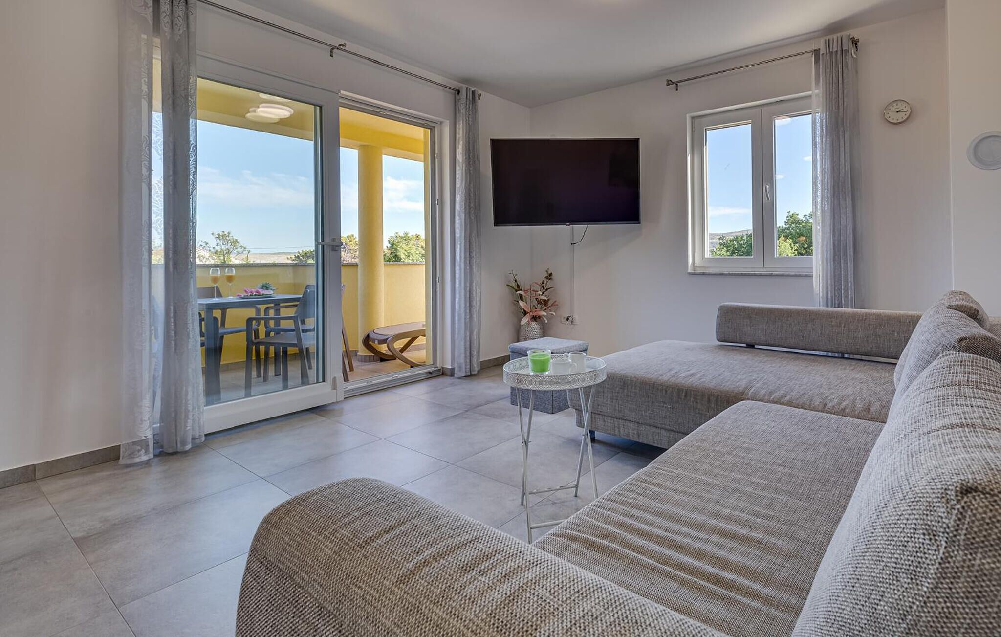 A modern living room with a sofa, a small table, and a TV mounted on the wall.