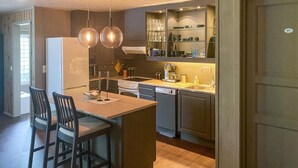 Una cocina moderna con una isla central, dos lámparas colgantes y un horno empotrado.