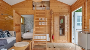 A wooden cabin with a loft bed, a dining area, and a kitchen.
