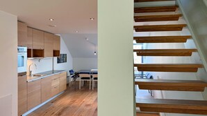 A modern kitchen with wooden cabinets, a built-in oven, and a dining area with a table and chairs. - 2 bedroom pet friendly apartment in Søgne (Søgne)