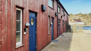 A row of red wooden buildings with blue doors, numbered 5, along a waterfront. - 2 bedroom pet friendly apartment in Søgne (Søgne)
