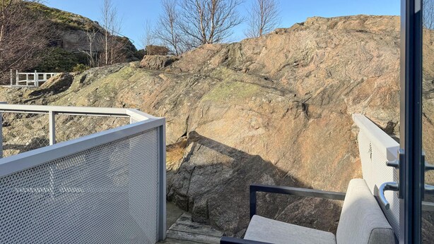 A wooden deck with a metal railing overlooking a rocky landscape. - 2 bedroom pet friendly apartment in Søgne (Søgne)