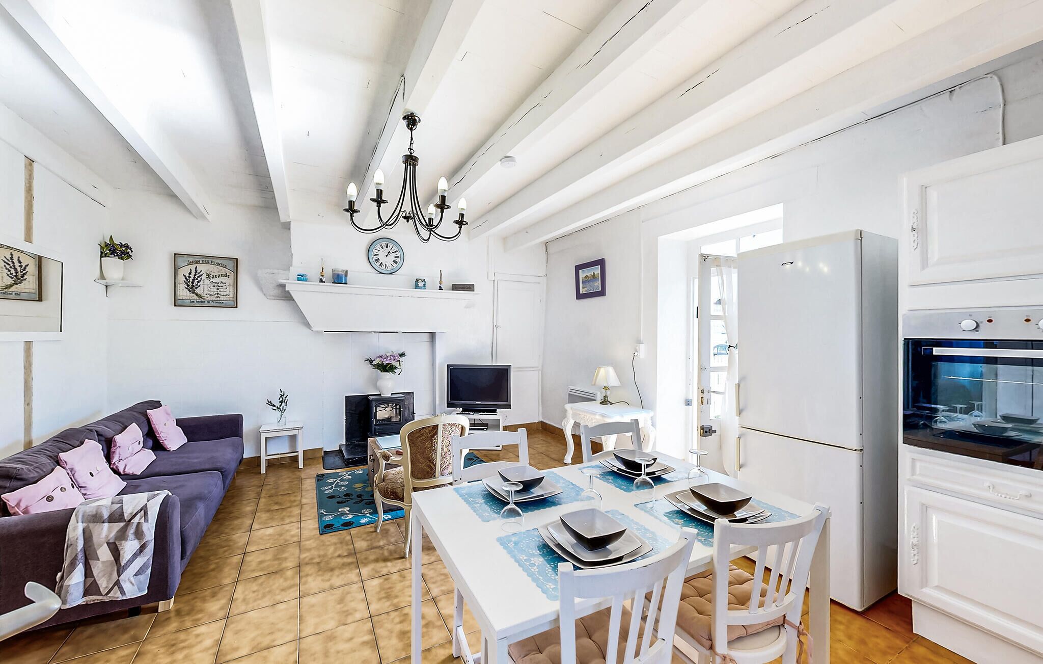 A spacious living room with a sofa, TV, and dining area with chairs and a table.
