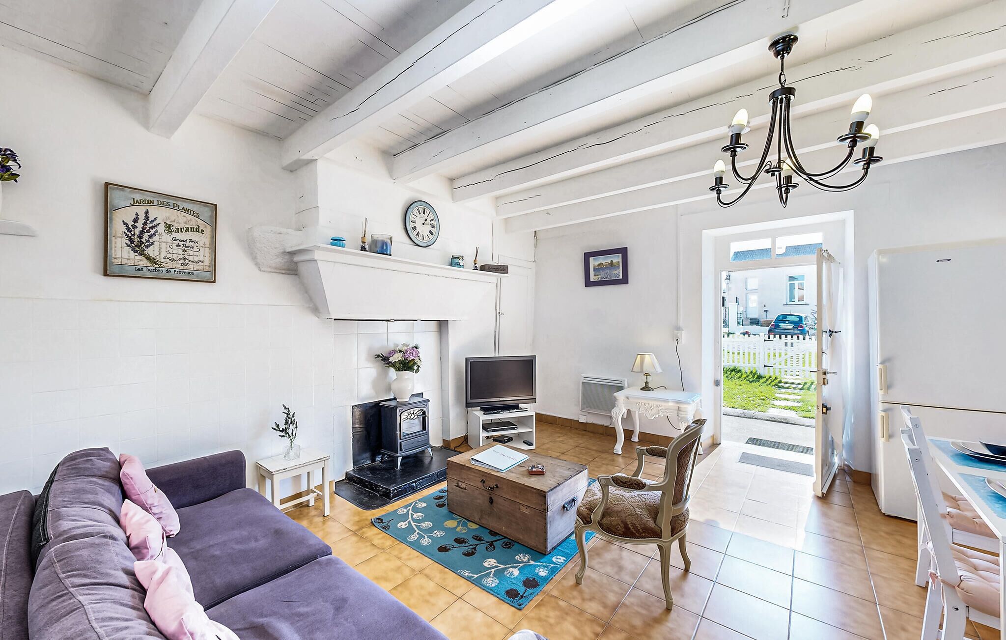 Een woonkamer met een bank, een televisie, een open haard, een kroonluchter en uitzicht op het omliggende landschap.