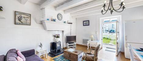 Een woonkamer met een bank, een televisie, een open haard, een kroonluchter en uitzicht op het omliggende landschap.