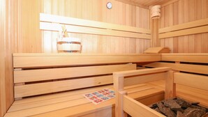A wooden sauna with benches, a sauna lamp, and a sauna heater. - Beautiful home in Stadl an der Mur (Stadl an der Mur)