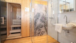 A modern bathroom with a glass shower enclosure, wooden paneling, a white sink, and a wooden bench. - Beautiful home in Stadl an der Mur (Stadl an der Mur)