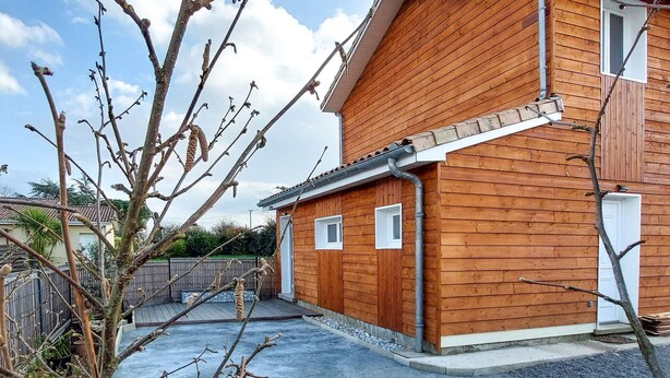 Une maison en bois avec un toit en pente, un petit porche et une porte de garage.
