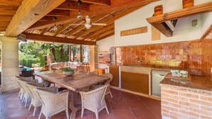 An outdoor kitchen with a dining area, wooden ceiling, and a view of the garden. - Amazing home in Son Servera (Son Servera)