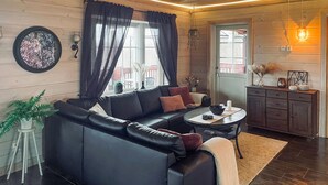 A cozy living room with a black leather sofa, a small round table, and a cabinet with decorative items. - Beautiful home in Charlottenberg (Charlottenberg)