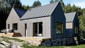 Een modern huis met een schuin dak, grote ramen en een stenen fundering.