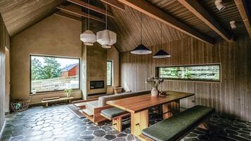 Ein rustikales Interieur mit Steinböden, Holzmöbeln und großen Fenstern mit Blick ins Freie.