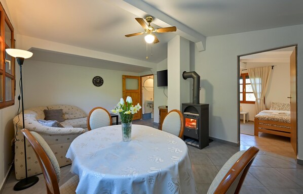A cozy living room with a round table, chairs, a sofa, a fireplace, and a ceiling fan.