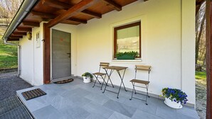A covered outdoor seating area with a table and chairs, a window with a plant, and a door. - 1 bedroom lovely home in Andrasevec (Andrasevec)