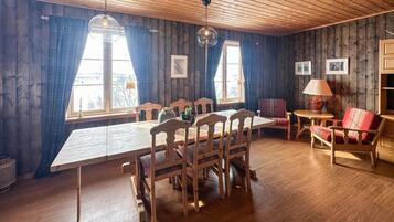 Ein Zimmer mit Holzwänden, einem Esstisch, Stühlen und einer Couch.
