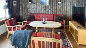 A cozy room with a wooden wall, a red sofa, a wooden coffee table, and a television on a wooden cabinet. - Awesome apartment in Rauland (Rauland)