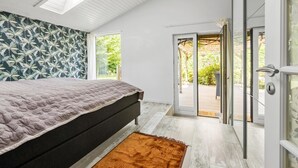 Un dormitorio con una cama, una ventana y una puerta abierta que da a un patio.