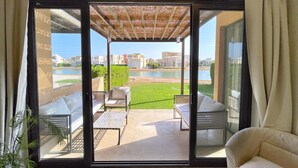 Ein Balkon mit Blick auf ein Gewässer und Gebäude, ausgestattet mit weißen Sofas und einem Tisch.
