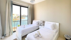 Ein Hotelzimmer mit zwei Betten, Blick auf ein Gewässer und einem Balkon.