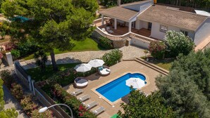 En bolig med swimmingpool, udendørs siddepladser og en overdækket patio.