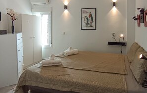A bedroom with a bed, towels, a wardrobe, a framed picture, wall sconces, and a small shelf. - Gorgeous apartment in Calahonda (Calahonda)