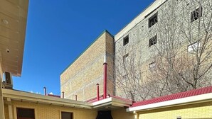 Un patio con un edificio de ladrillo, una chimenea y mobiliario para exteriores.
