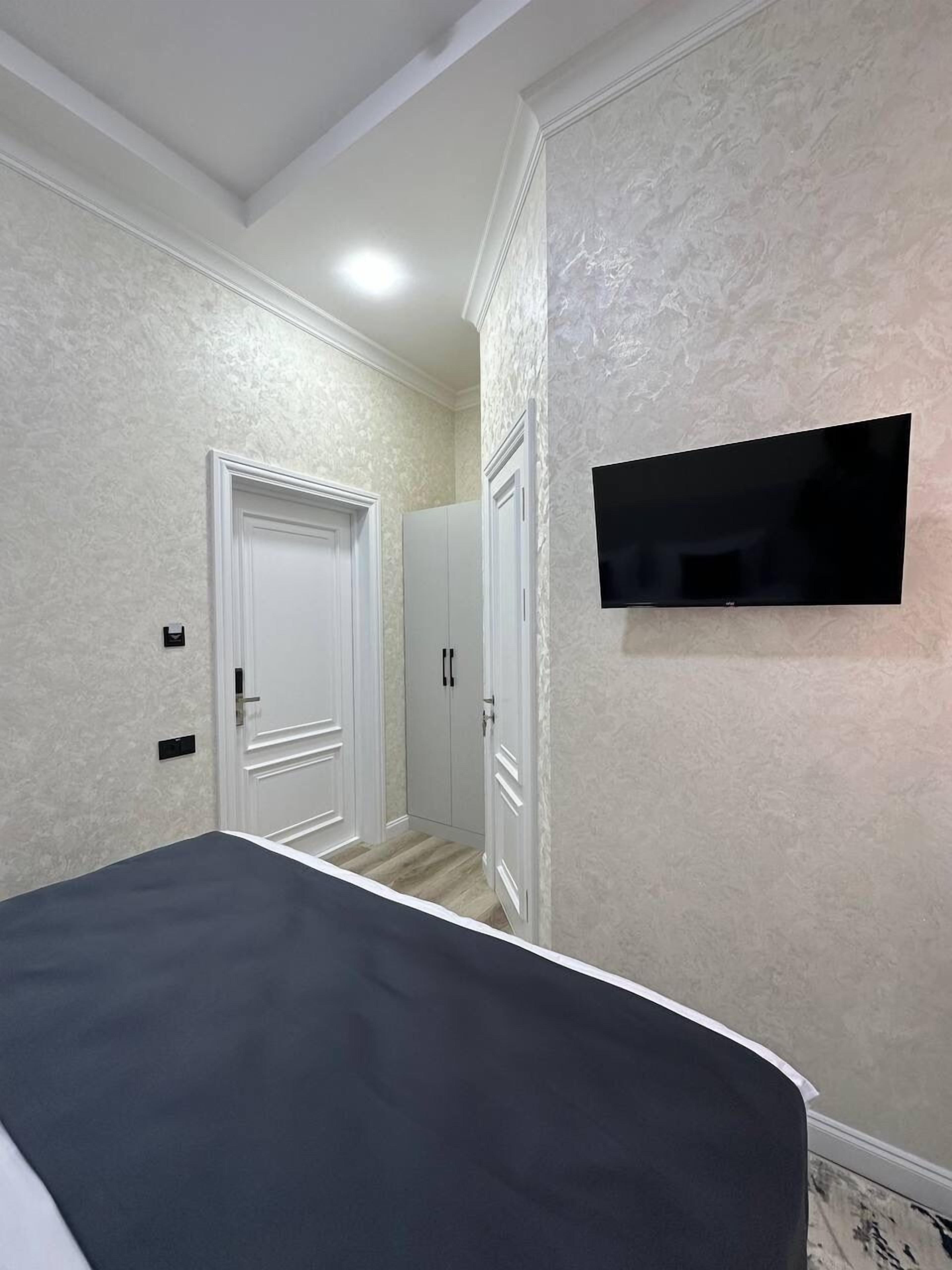 Een slaapkamer met een bed, een aan de muur bevestigde televisie en een kledingkast.