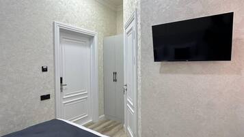 Een slaapkamer met een bed, een aan de muur bevestigde televisie en een kledingkast.