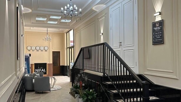 Un pasillo espacioso con una imponente escalera, un candelabro y un cartel que indica el camino al restaurante.