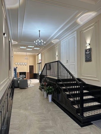 A spacious hallway with a grand staircase, a chandelier, and a sign indicating the direction to the restaurant.