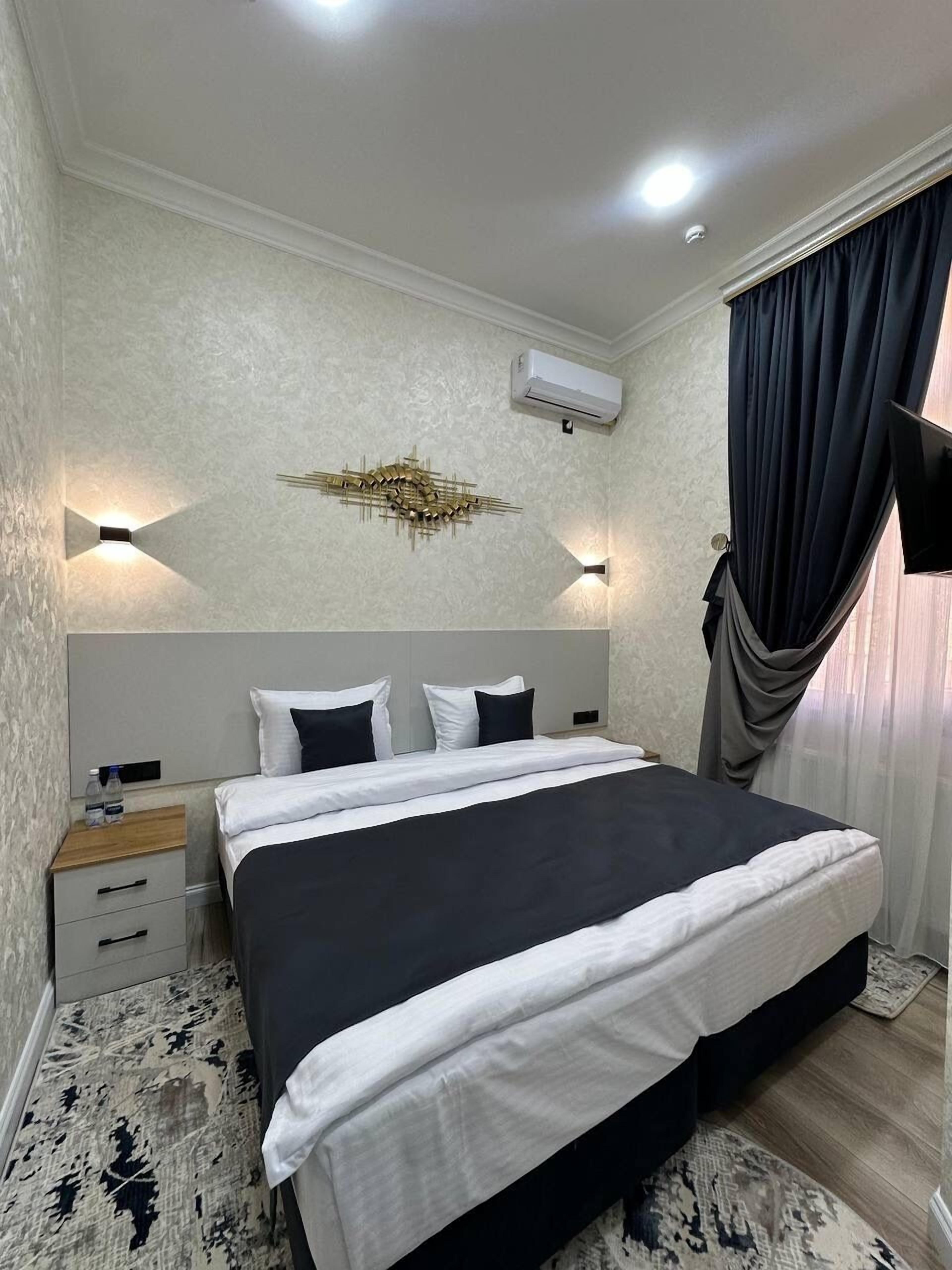 Une chambre à coucher bien aménagée, avec un grand lit, des tables de chevet, un appareil de climatisation et un luminaire fixé au mur.