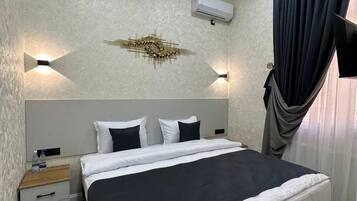 Une chambre à coucher bien aménagée, avec un grand lit, des tables de chevet, un appareil de climatisation et un luminaire fixé au mur.