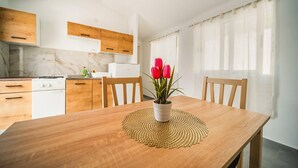 Une cuisine moderne avec des meubles en bois, un fourneau blanc et un coin repas comprenant une table et des chaises en bois.