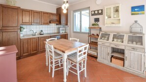A kitchen with wooden cabinets, a white tiled backsplash, a wooden dining table with white chairs, and a window with natural light. - Nice apartment in Terranuova Bracciolini (Terranuova Bracciolini)
